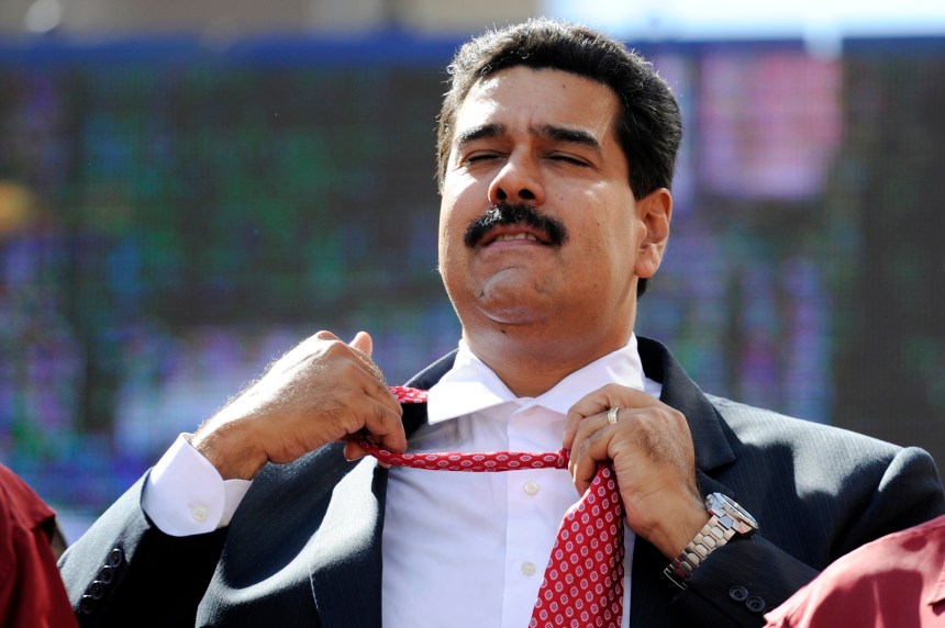 Venezuelan President Nicolas Maduro unties his tie during a rally in Caracas on November 12, 2013. Venezuela's ruling party eyed a vote Tuesday to pave the way for Maduro to govern by decree, broadening his powers, during an inflationary crisis a month before crucial municipal elections. AFP PHOTO/Leo RAMIREZ (Photo credit should read LEO RAMIREZ/AFP/Getty Images)