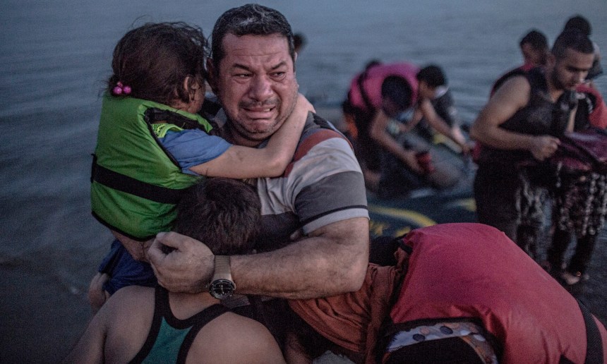 A Syrian refugee holding his son and daughter